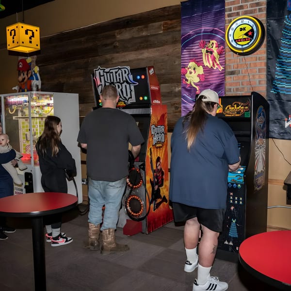 Patrons playing Guitar Hero and Galaga arcade games at The Pickled Goat Bar & Grill.