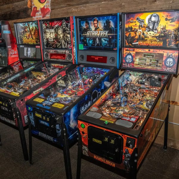 A row of themed pinball machines, including Jurassic Park, Walking Dead, Star Trek, and Mandalorian.