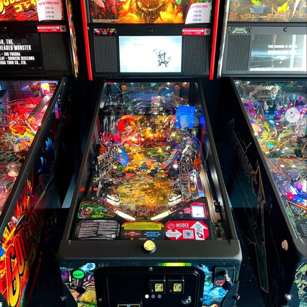 Three vibrant pinball machines, including Godzilla and Metallica, at The Pickled Goat Bar & Grill.