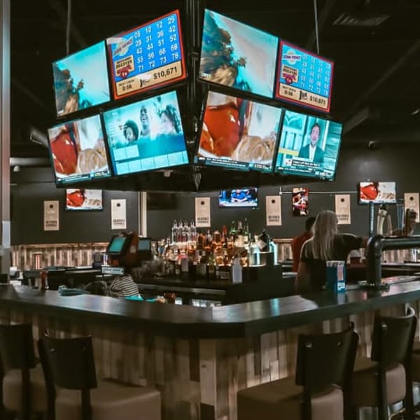 The Pickled Goat Bar & Grill's bar area with multiple TVs showing sports and games, and patrons.